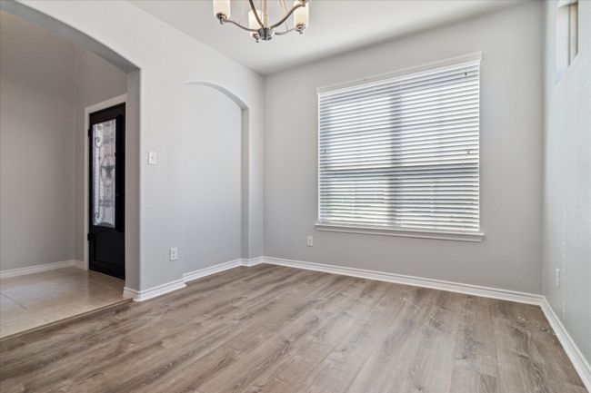 Spare room with baseboards, arched walkways, an inviting chandelier, and wood finished floors | Image 4