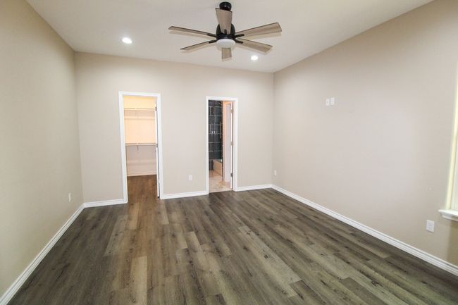 Primary bedroom with a spacious walk-in closet, dark wood finished floors, recessed lighting, and a ceiling fan | Image 10