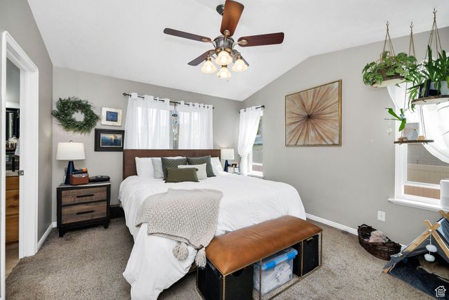 Main bedroom with ensuite featuring carpet, lofted ceiling, baseboards, and a ceiling fan | Image 22