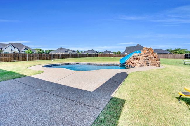 View of pool featuring a water slide, a fenced backyard, a residential view, and a patio | Image 33