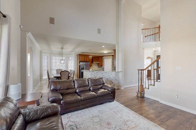 Living area with arched walkways, dark wood-style flooring, a towering ceiling, and baseboards | Image 6