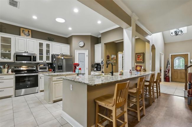 Kitchen with appliances with stainless steel finishes, light tile patterned flooring, arched walkways, a breakfast bar, and a kitchen island | Image 14