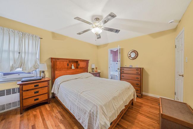 Bedroom with radiator, wood finished floors, ceiling fan, and connected bathroom | Image 13