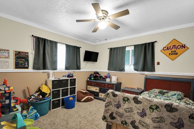 Bedroom featuring carpet, crown molding, a textured ceiling, and a ceiling fan | Image 9