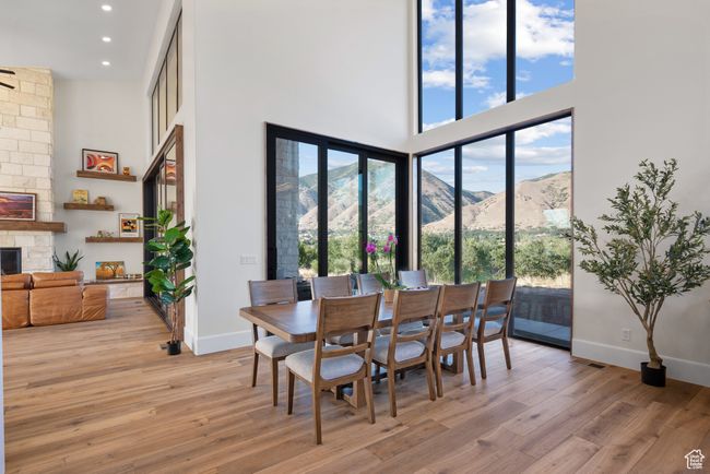 Dining area featuring a high ceiling, a stone fireplace, light wood finished floors, recessed lighting, and a mountain view | Image 24
