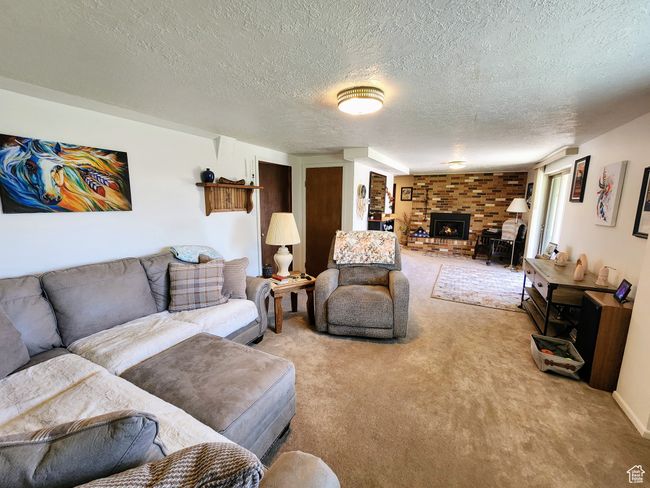 Living area with light colored carpet, a wood stove, and a textured ceiling | Image 32