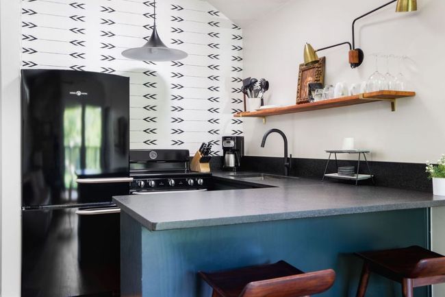 Kitchen featuring dark countertops, a sink, open shelves, a breakfast bar area, and black appliances | Image 22