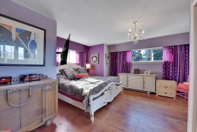 Bedroom featuring multiple windows, a chandelier, a textured ceiling, and hardwood / wood-style flooring | Image 32