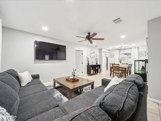 Living area with ceiling fan, recessed lighting, light tile patterned floors, and baseboards | Image 4