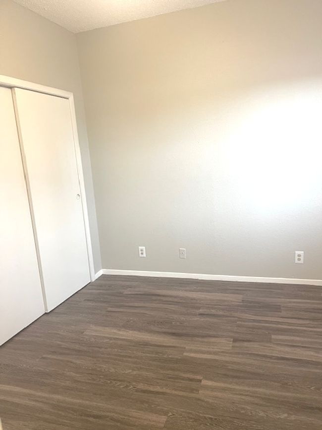 Unfurnished bedroom with dark wood finished floors, a closet, and baseboards | Image 9