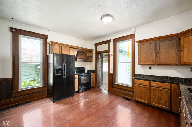 kitchen with black appliances, a textured ceiling, dark countertops, dark wood finished floors, and brown cabinets | Image 7