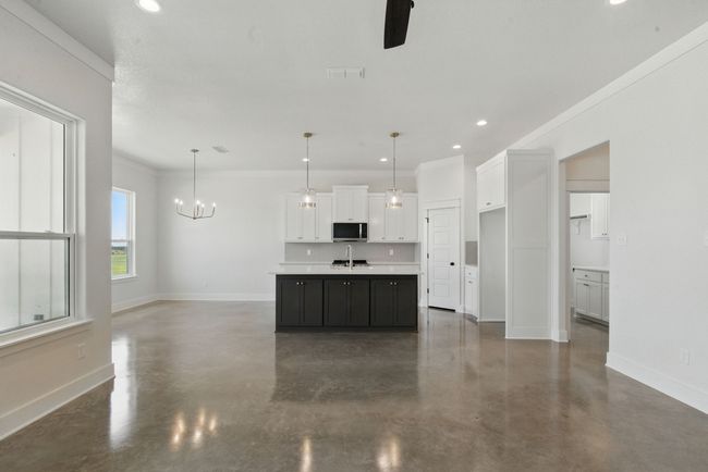Kitchen featuring stainless steel microwave, concrete floors, a sink, white cabinetry, and recessed lighting | Image 5