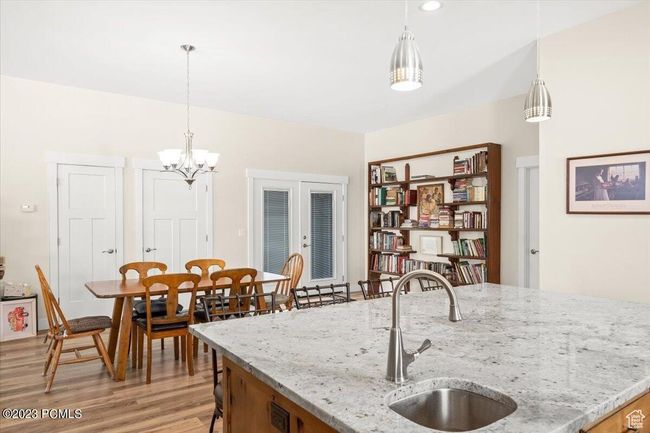 Kitchen featuring light wood-type flooring, pendant lighting, a chandelier, and light stone countertops | Image 14
