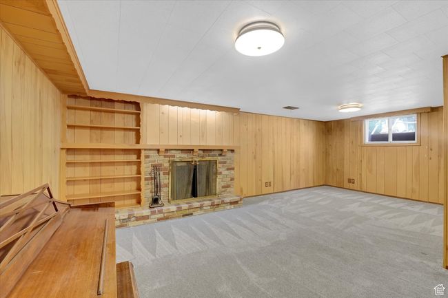 Unfurnished living room featuring wooden walls, carpet flooring, and a fireplace | Image 20