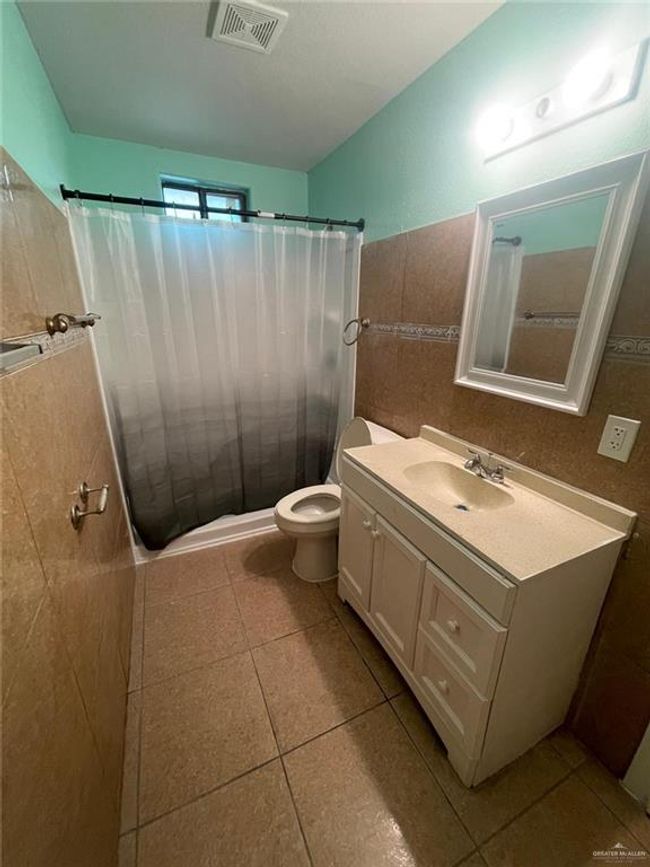 Full bath featuring vanity, a shower with curtain, visible vents, tile patterned floors, and toilet | Image 8