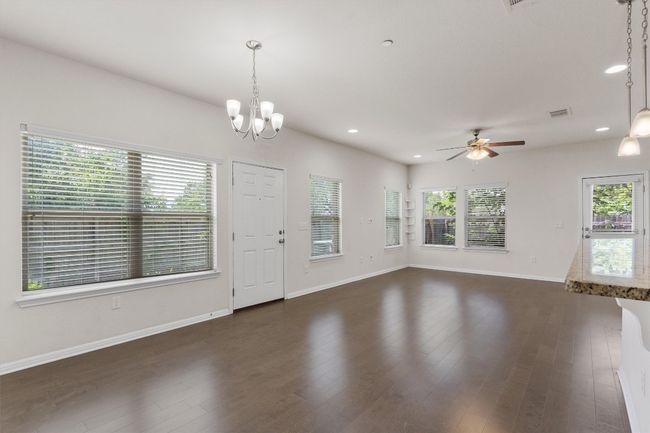 Unfurnished living room with healthy amount of natural light, a ceiling fan, dark wood-style floors, and recessed lighting | Image 8