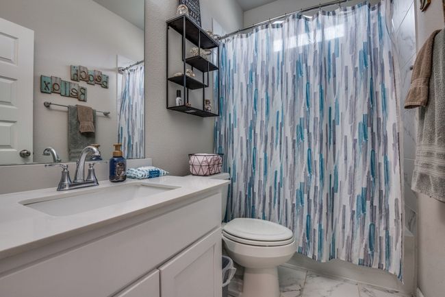 Bathroom with marble look tile flooring, vanity, and curtained shower | Image 17
