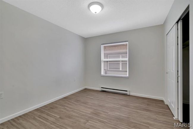 Unfurnished bedroom with a baseboard radiator, a closet, a textured ceiling, and LVP floors | Image 11