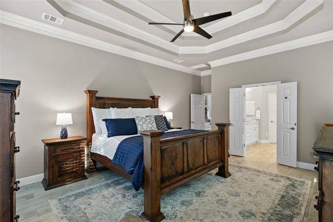 Primary Bedroom with a raised ceiling, ornamental molding, light ceramic tile wood-style floors, and a ceiling fan | Image 14