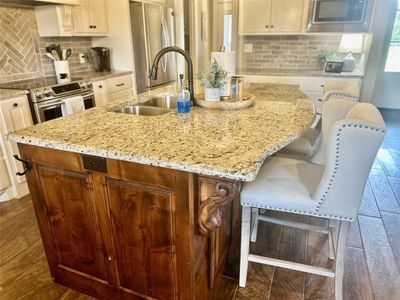 Kitchen featuring appliances with stainless steel finishes, light stone countertops, sink, a breakfast bar area, and a center island with sink | Image 3