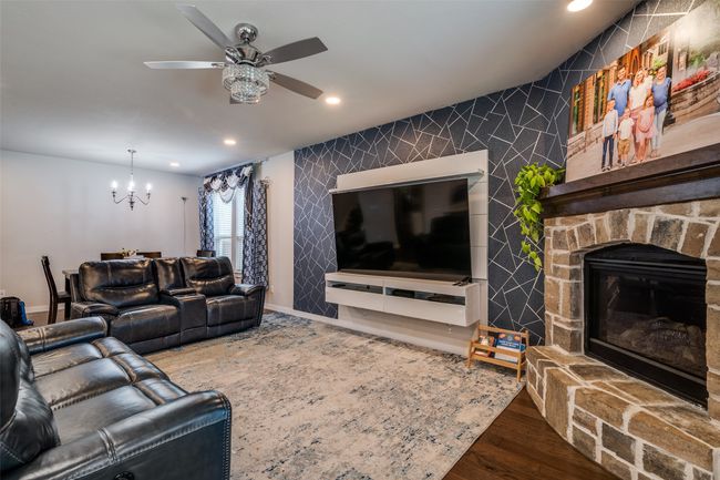 Living room with a chandelier, an accent wall, recessed lighting, ceiling fan, and wood finished floors | Image 9