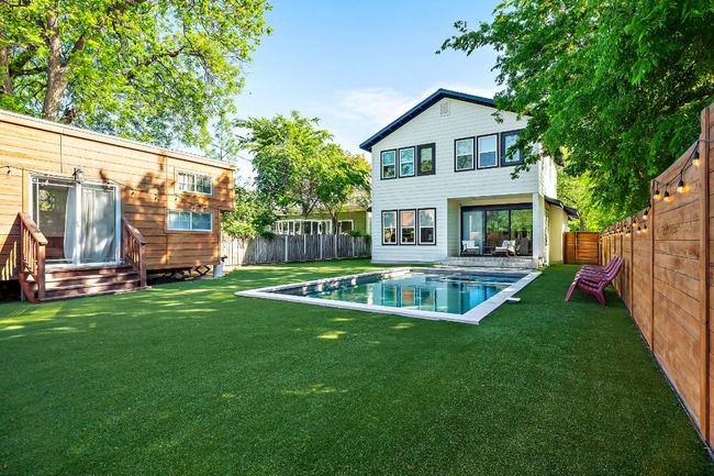 Back of property featuring a fenced backyard, a yard, a fenced in pool, and entry steps | Image 33