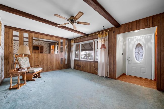 Foyer featuring light carpet, wood walls, beam ceiling, and a ceiling fan | Image 7
