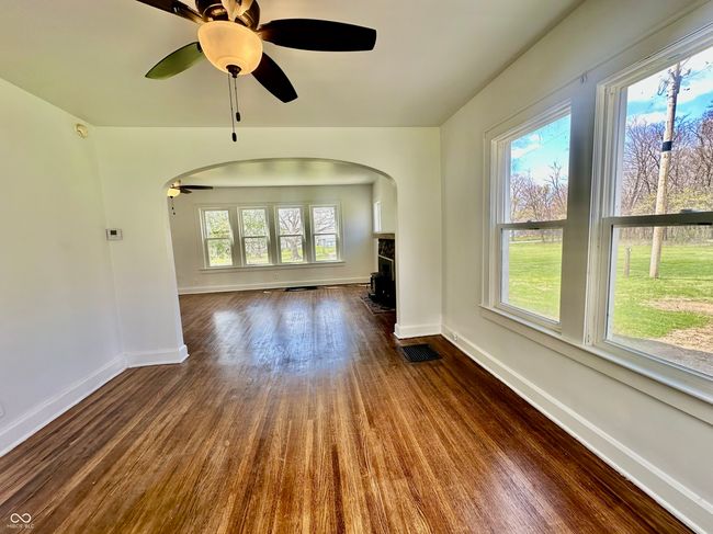 unfurnished living room with ceiling fan, arched walkways, visible vents, dark wood-style flooring, and baseboards | Image 26