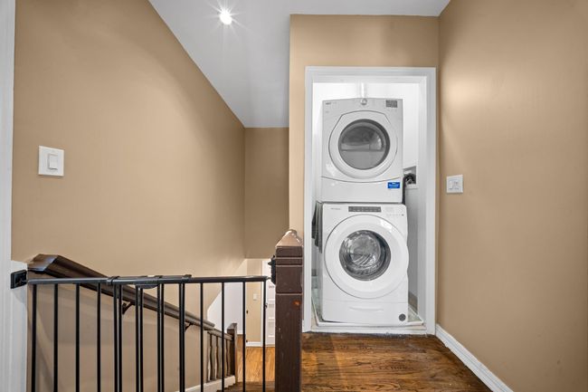 Laundry area featuring stacked washer / drying machine, wood finished floors, and baseboards | Image 27