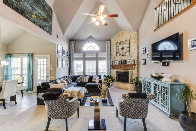 Living room with tile patterned floors, ceiling fan, a fireplace, and high vaulted ceiling | Image 10