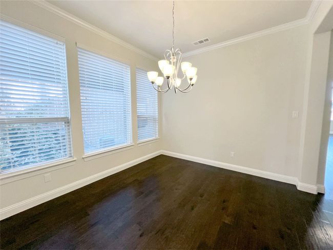 Unfurnished dining area with a chandelier, dark wood-style floors, and crown molding | Image 6