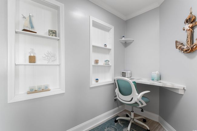 Office space with built in desk, baseboards, wood finished floors, and crown molding | Image 12