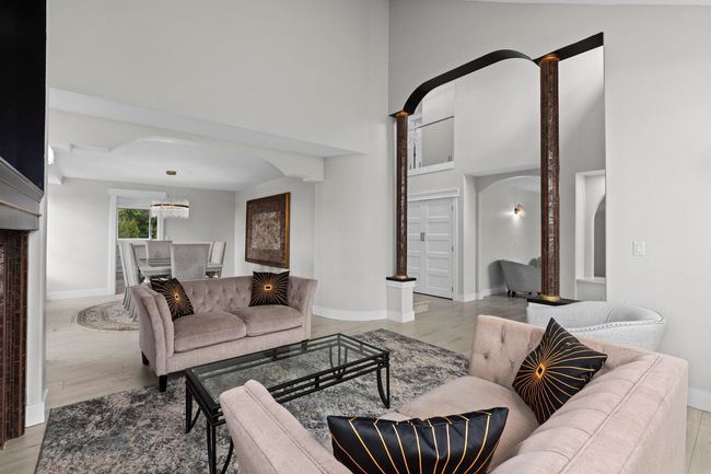 Living room featuring arched walkways, a towering ceiling, baseboards, and light wood-type flooring | Image 5