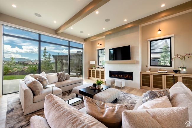Living room featuring a glass covered fireplace, light wood-style floors, recessed lighting, and beam ceiling | Image 12