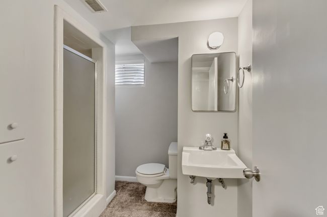 Full bathroom featuring a shower stall, a sink, baseboards, toilet, and visible vents | Image 15