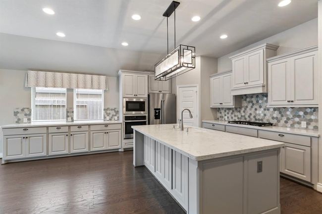 Kitchen also has Island with Sink and Upgraded Cabinet and Countertop area, with Beautiful Counter Tops and Backsplash. Light Fixture along with LED Lighting, makes Kitchen Bright. Refrigerator Included! | Image 9