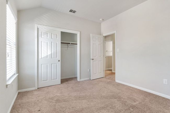 Unfurnished bedroom with multiple windows, visible vents, lofted ceiling, and carpet flooring | Image 30