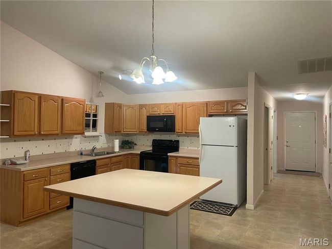 Kitchen with black appliances, open shelves, a chandelier, light countertops, and vaulted ceiling | Image 6