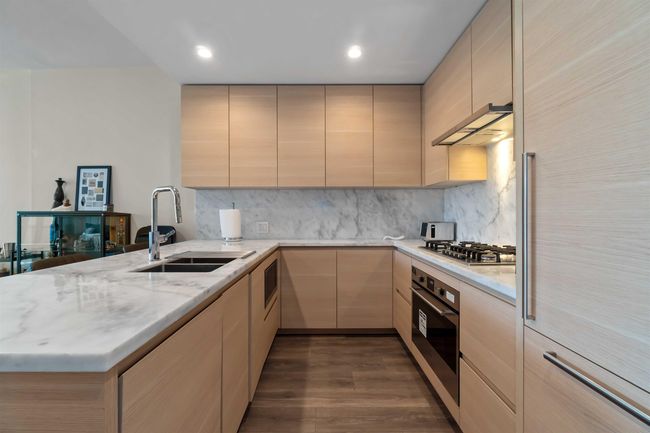 Kitchen with exhaust hood, a sink, stainless steel appliances, light brown cabinetry, and a peninsula | Image 14