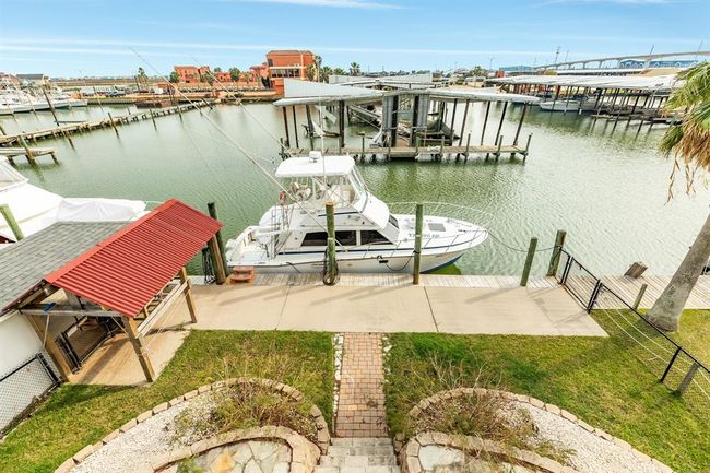 56 Marlin Deck View showcases a waterfront property with boat access. The area features a well-maintained lawn, paved walkway, and a covered fishing station, offering scenic water views and convenient boating opportunities. | Image 28