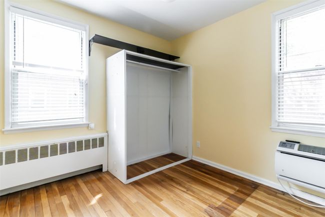 Bedroom with 2 exposures, hardwood floors, and a wall mounted AC | Image 8