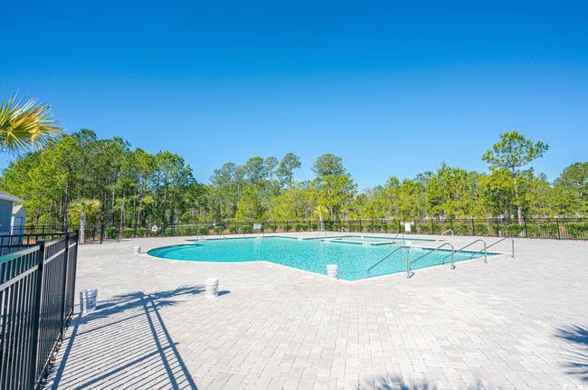 Community pool with fence, a patio area, and view of wooded area | Image 40