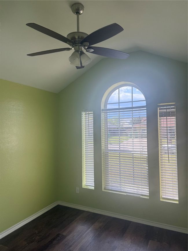 Spare room with a ceiling fan, dark wood-style floors, lofted ceiling, and baseboards | Image 11