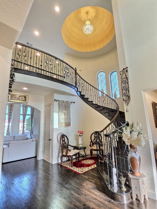 Stairs featuring a towering ceiling, healthy amount of natural light, baseboards, wood finished floors, and arched walkways | Image 19