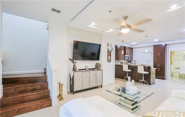Living room featuring ceiling fan, a raised ceiling, and light tile patterned floors | Image 18