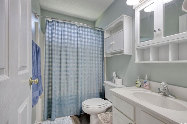 Full bathroom featuring vanity, shower / bathtub combination with curtain, wood finished floors, and a textured ceiling | Image 24