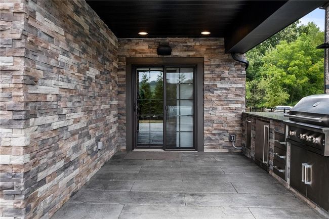 Lower Level door to rear stamped patio. Lower Level rear patio has built-in trash, grill, storage drawers, and mini fridge! | Image 42
