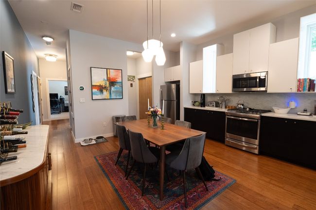 Kitchen with appliances with stainless steel finishes, light countertops, backsplash, white cabinets, and wood finished floors | Image 22