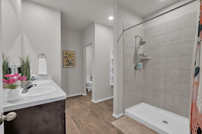 Say hello to the primary bathroom featuring a walk-in shower, built in shelving, dual sinks, and low maintenance vinyl flooring. | Image 18