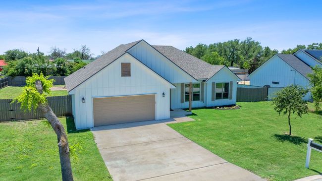 View of front of house with roof with shingles, a garage, concrete driveway, and board and batten siding | Image 35